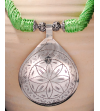 Détail de collier pendentif Nomade fait main de style ethnique chic fabriqué en soie de sabra et métal argenté en pistache