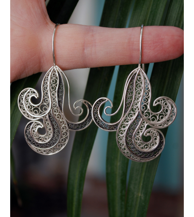Handgefertigte filigrane "Onda"-Ohrringe aus natürlichem und oxidiertem Silber, die am Finger einer Frau hängen