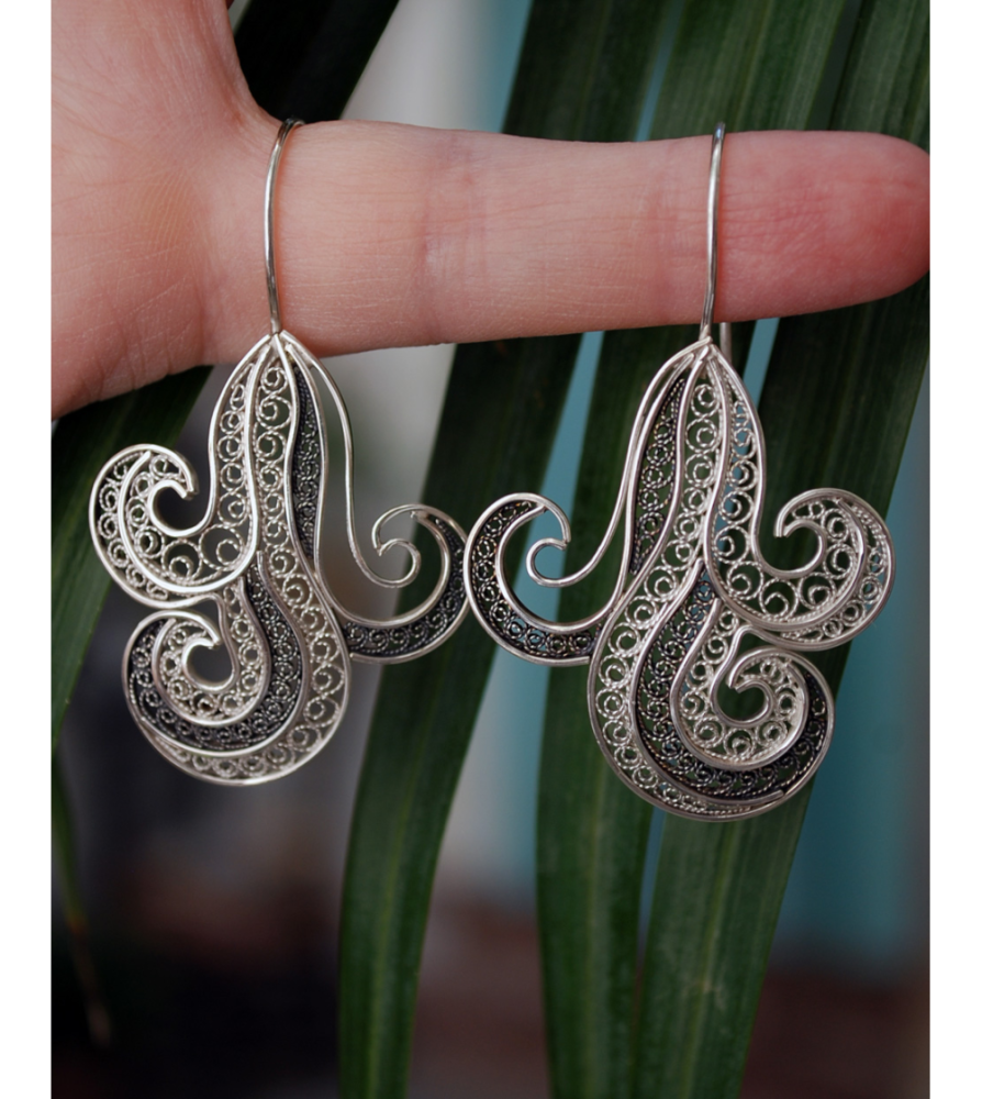 Pendientes de filigrana "Onda" hechos a mano de plata natural y oxidada mostrados colgando de un dedo de mujer