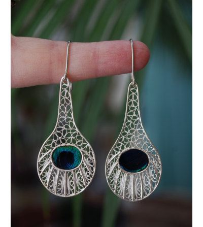Stunning filigree "Peacock" drop earrings handmade from 925 silver shown to scale hanging from a woman´s finger