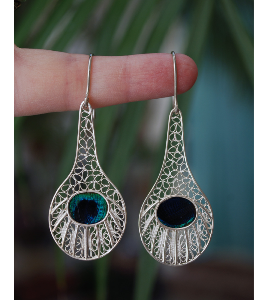 Stunning filigree "Peacock" drop earrings handmade from 925 silver shown to scale hanging from a woman´s finger