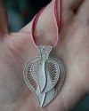 Pendentif filigrane "Coeur de Feuille" double fait main d´argent 925 montré à la taille dans la main d´une femme