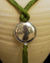 Détail de collier pendentif art déco ethnique fait main en soie de sabra en vert anise avec sphère argentée martelée à pompon