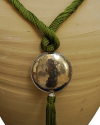 Détail de collier pendentif art déco ethnique fait main en soie de sabra en vert anise avec sphère argentée martelée à pompon