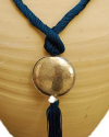 Detail of art déco pendant necklace in petrol blue and a hammered silver sphere with hanging tassel on white backdrop