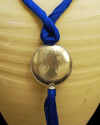 Détail de collier pendentif art déco ethnique fait main en soie de sabra en bleu royal avec sphère argentée martelée à pompon