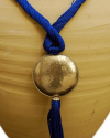 Detail of art déco pendant necklace in royal blue and a hammered silver sphere with hanging tassel on white backdrop