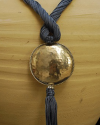 Detail of art déco pendant necklace in grey blue and a hammered silver sphere with hanging tassel