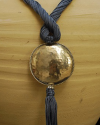 Détail de collier pendentif art déco ethnique fait main en soie de sabra en gris bleu avec sphère argentée martelée à pompon