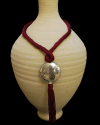 Hand made ethnic chic art déco pendant necklace made from sabra silk in light bordeaux and a hammered silver sphere with tassel