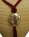 Detail of art déco pendant necklace in light bordeaux and a hammered silver sphere with hanging tassel