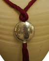 Detalle de colgante arte déco con esfera plateada con felquillo con cadena de seda de sabra en burdeos claro de estilo étnico