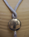Detail of art déco pendant necklace in light grey and a hammered silver sphere with hanging tassel