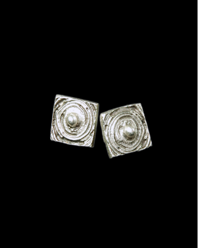 Vue de face des clous d'oreilles de forme carrée à motif "Planète" en zamak plaqué argent oxydé chez Andaluchic sur un fond noir