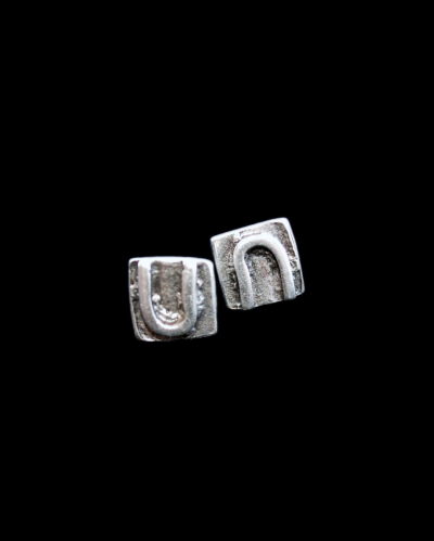 Front view of Andaluchic´s "U" motif stud earrings made in oxidised silver plated zamak on a black background