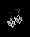 Front view of Andaluchic´s "Calligraphy" motif drop earrings in oxidised silver plated zamak displayed on a black backdrop