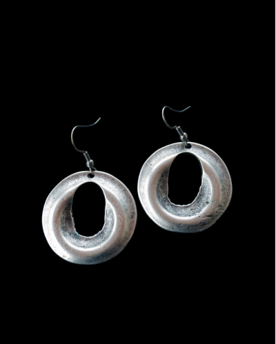 Vista frontale dei lunghi orecchini "Disco" di Andaluchic in zama placcata argento ossidato su sfondo nero