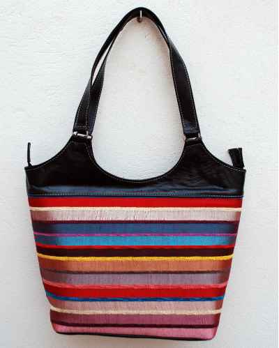 Large black leather shoulder bag with bright striped handwoven textile