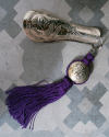Hand engraved silver shoehorn with decorative tassel in violet shown on a grey decorative Spanish tile @ Andaluchic