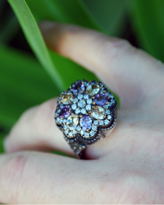 Vista superior del anillo de cóctel de flores hecho en plata 925 oxidada con circones claros, violetas y albaricoque