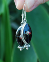 Long Oval drop earrings hand made in silver inset with semi-precious stones of black onyx with a small central red coral