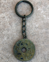 Vue d'oiseau d'un porte-clés plat et rond fait à la main en cuivre et gravé de l'alphabet phénicien sur un carreau de terre cuit