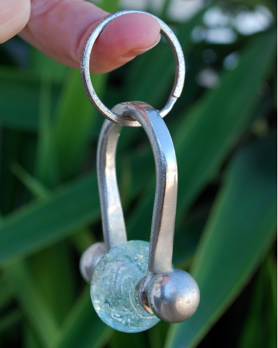 Versilberter Kupfer-Schlüsselanhänger mit klarer Glasperle das perfekte Geschenk , das an einem Finger hängend gezeigt wird