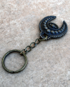 Side overview of a handmade copper phoencian keyring with a motif of a crescent moon combined with evil eye