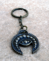 Front flat view of a handmade copper phoencian keyring with a motif of a crescent moon combined with evil eye