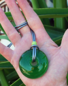Pendentif de verre soufflé verte en style ethnique-chic avec un fermoir en argent montré à la taille dans la main d´une femme